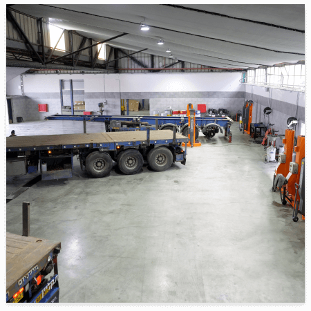 מילניום מרכז שירות למשאיות מרצדס באשדוד, משטח עבודה של המוסך עם משאיות בזמן עבודה תמונה מתוך המוסך